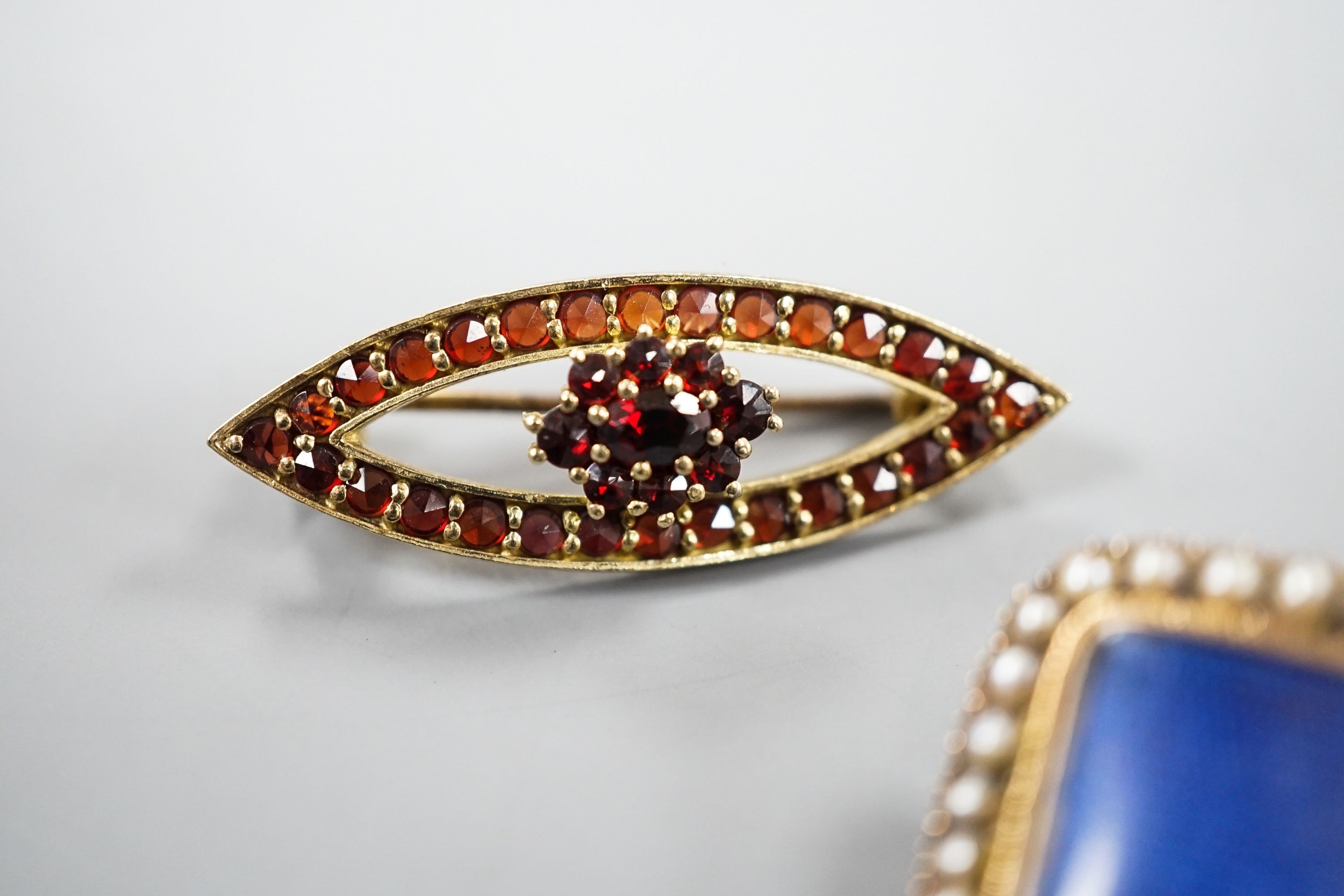 A Victorian yellow metal and spit pearl set mourning brooch, 23mm and 900 git white metal and garnet set brooch.